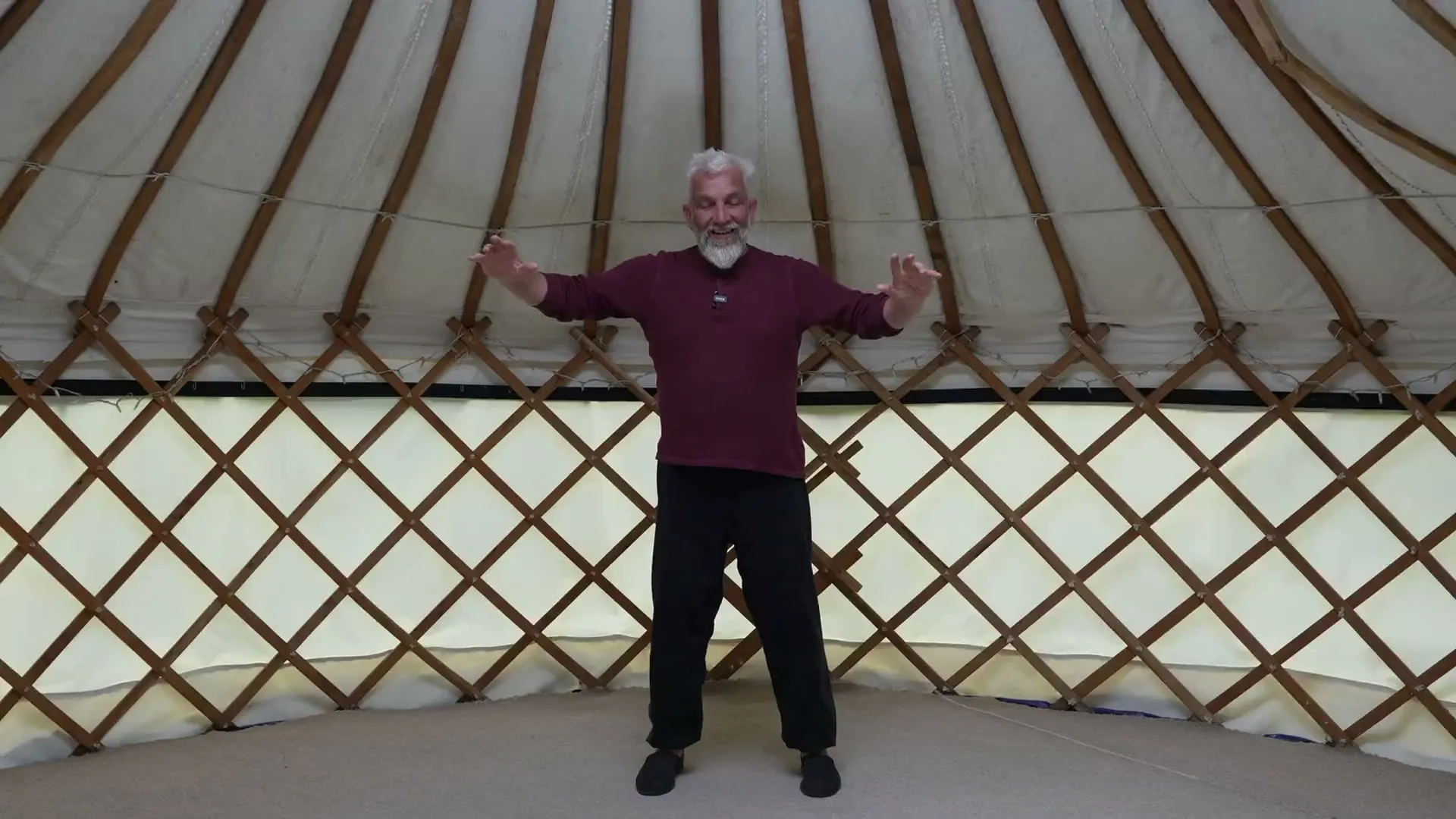John Millar practising Qi Gong inside a yurt, arms raised