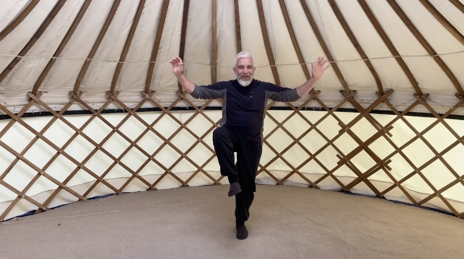 A practitioner balancing mid-movement inside a yurt