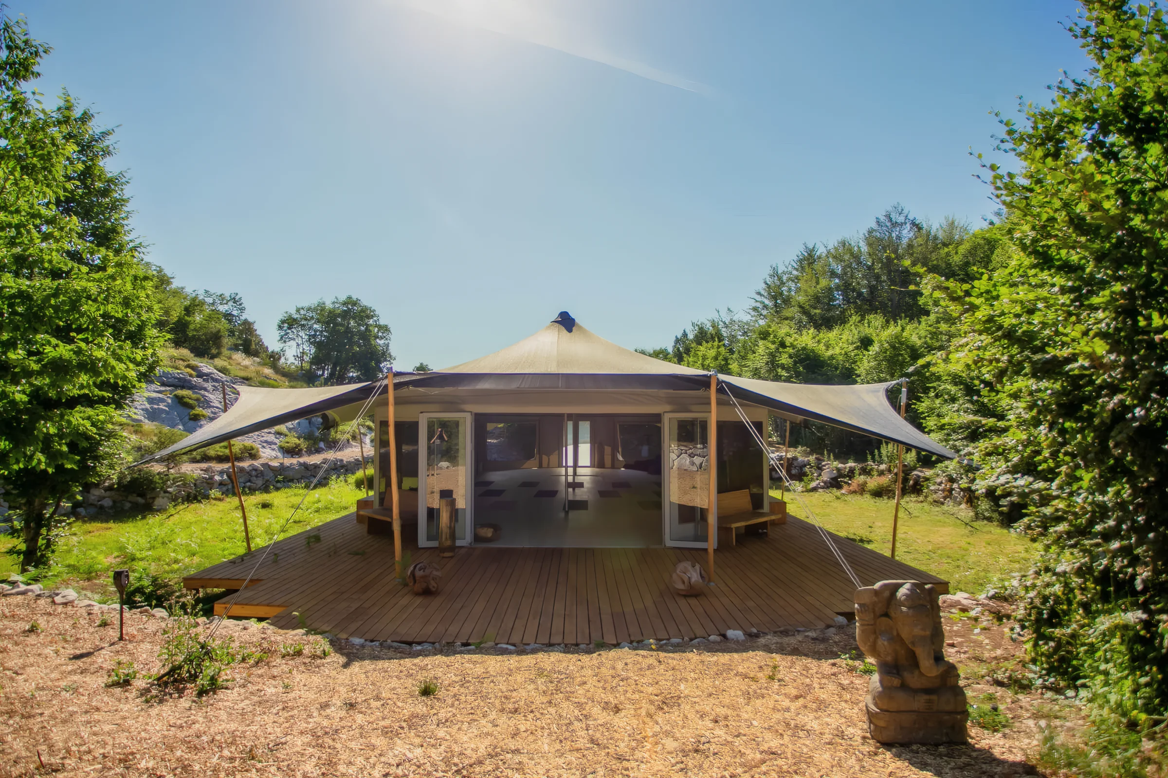 The practice pavilion at ašuma retreat in morning sun, surrounded by trees
