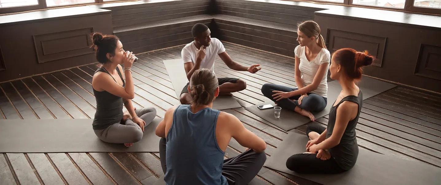 A small group sitting in a circle on a wooden floor