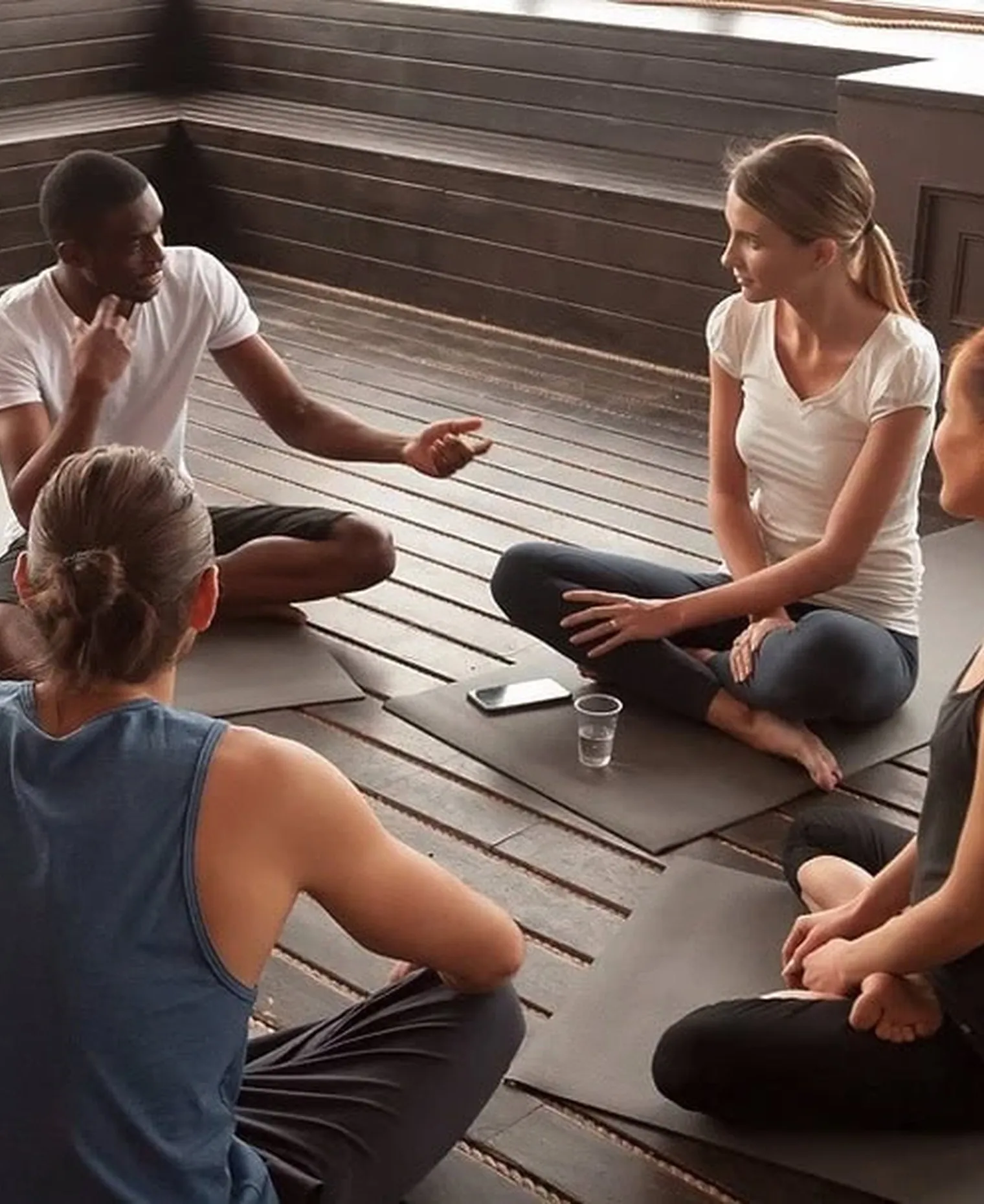 A small group sitting together on a wooden floor in discussion